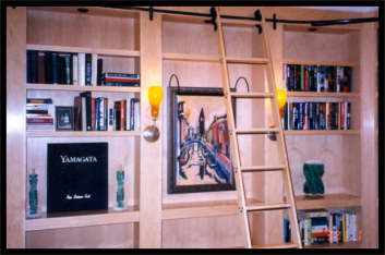 Maple built-in bookcase with clear coat finish, rolling ladder, and integrated sconce lights.